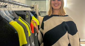 Young woman standing next to line of protective clothing.